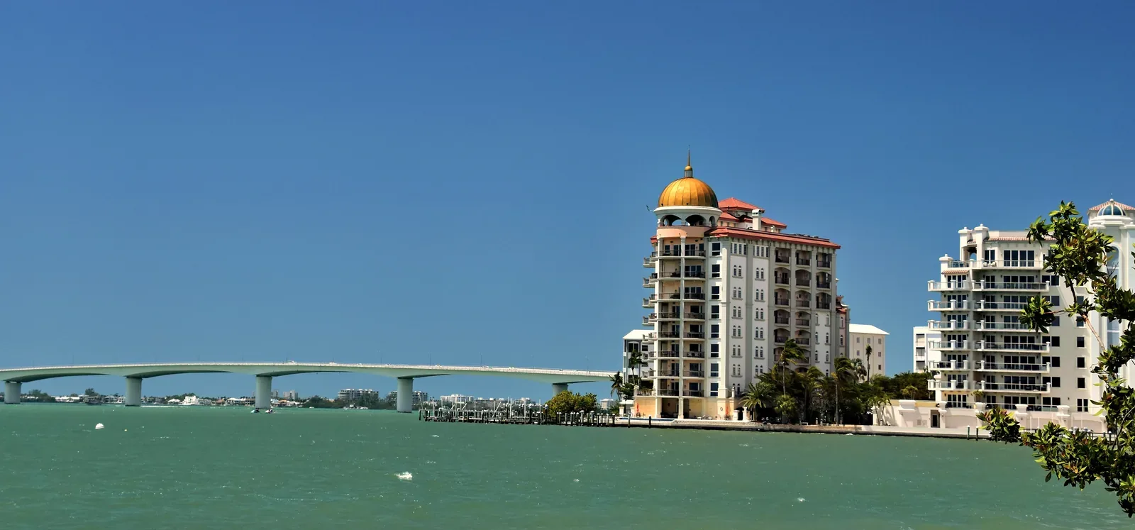 The Ringling Bridge across Sarasota Bay beside the bayfront towers on a sunny day.
